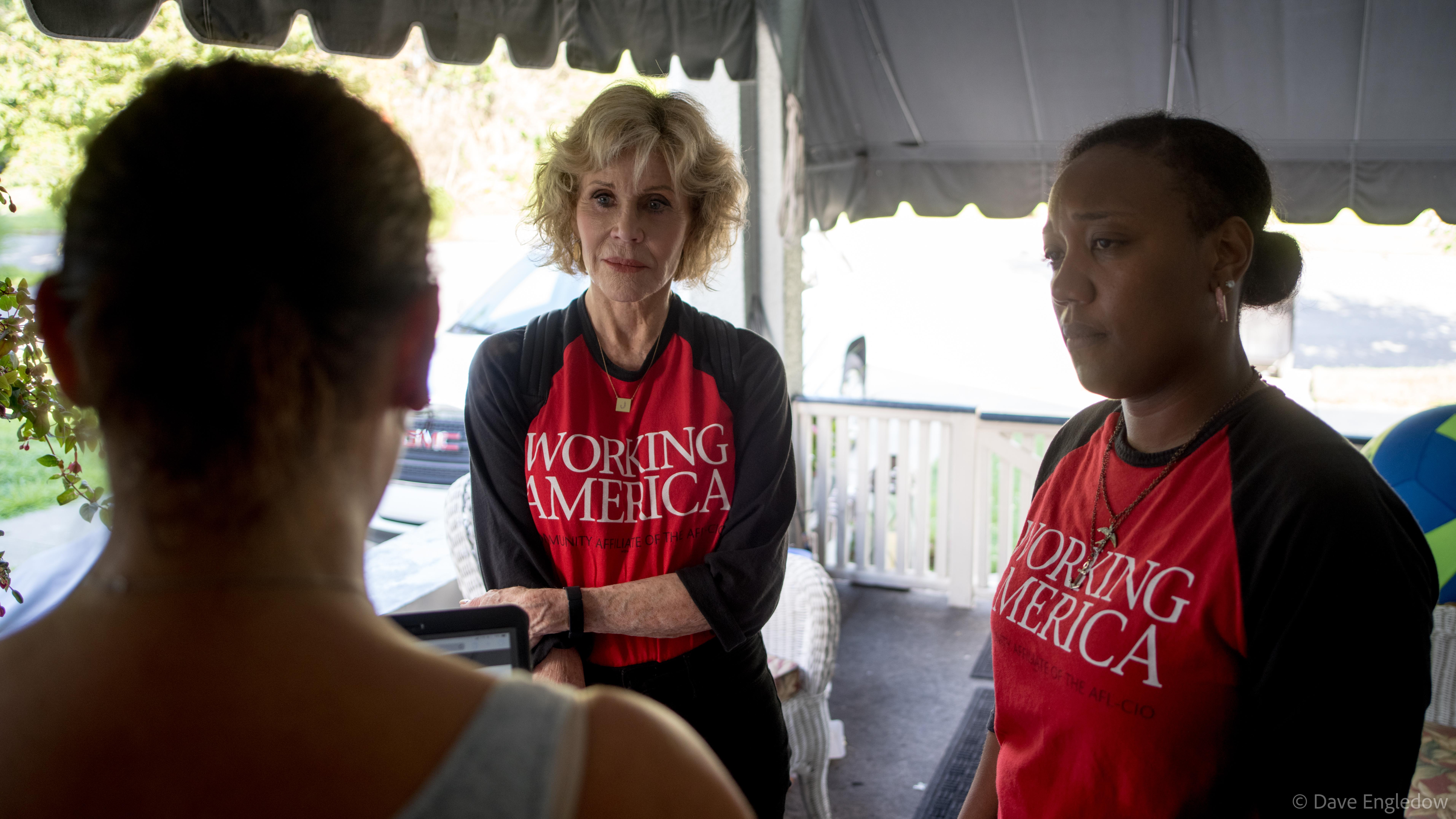 Jane Fonda and a canvasser listening to a woman speak on her porch